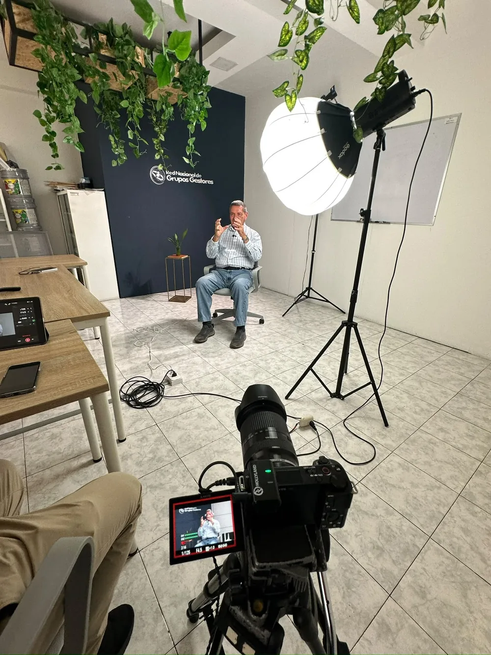 Entrevistado sentado frente al fondo institucional durante el rodaje